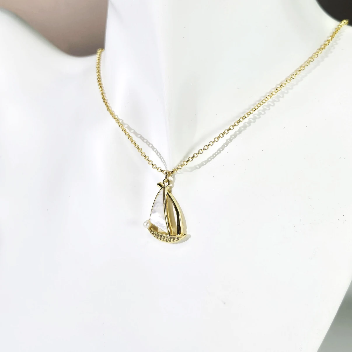 Gold sailboat necklace styled on display bust